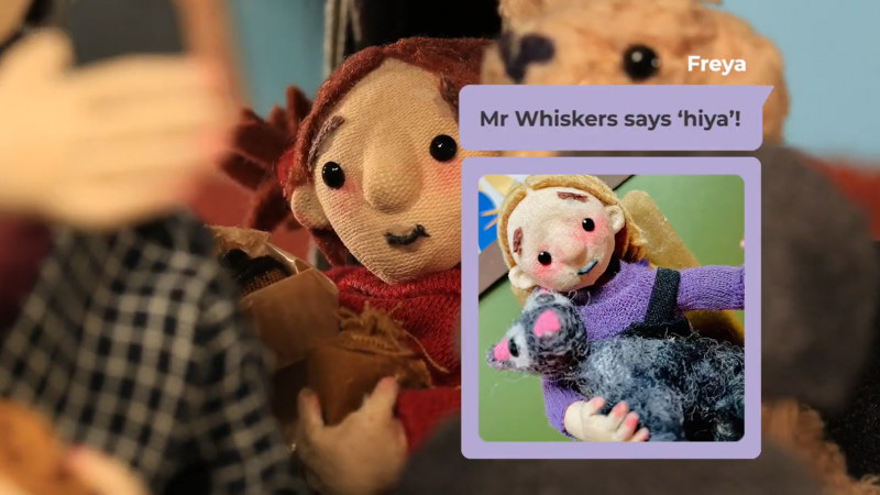 A screenshot from the animated video 'Part 3: We have lift off' showing a small girl in a car being shown a text on her foster carers phone of a small girl, Freya, hugging a cat, Mr Whiskers in Freya's new foster home. 